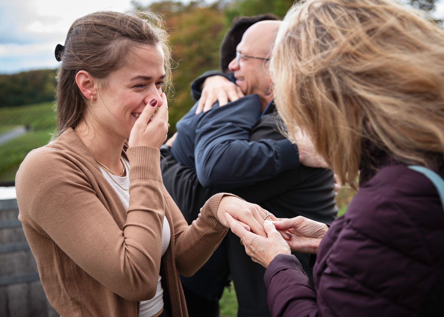 Emotional woman covers mouth in tears during a heartfelt outdoor family celebration moment.