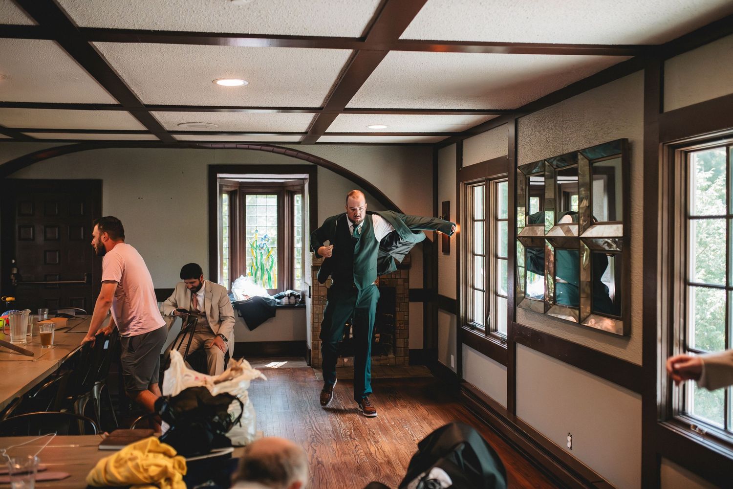 People gather in a long hallway with wooden beams and natural lighting for a group activity.