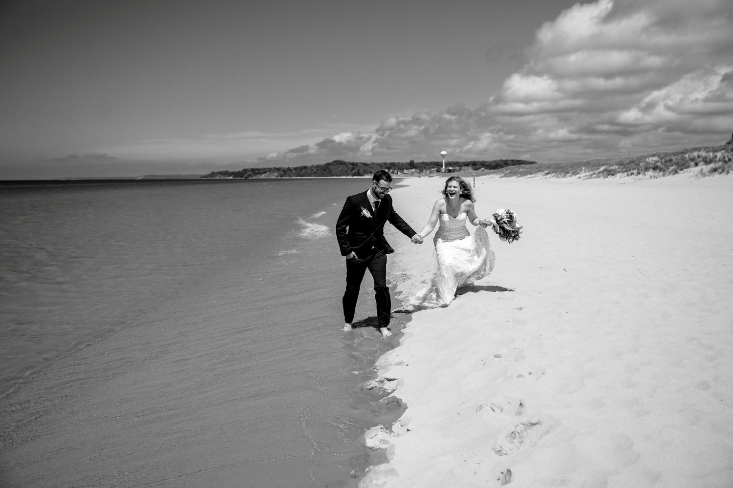 Black and white beach wedding photos show romantic moments between a couple celebrating their special day by the ocean.