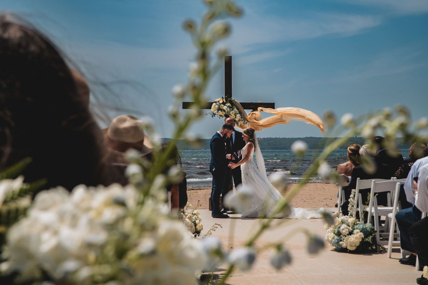 Outdoor wedding ceremony setup with rows of white chairs against a bright blue sky with desert plants in view.