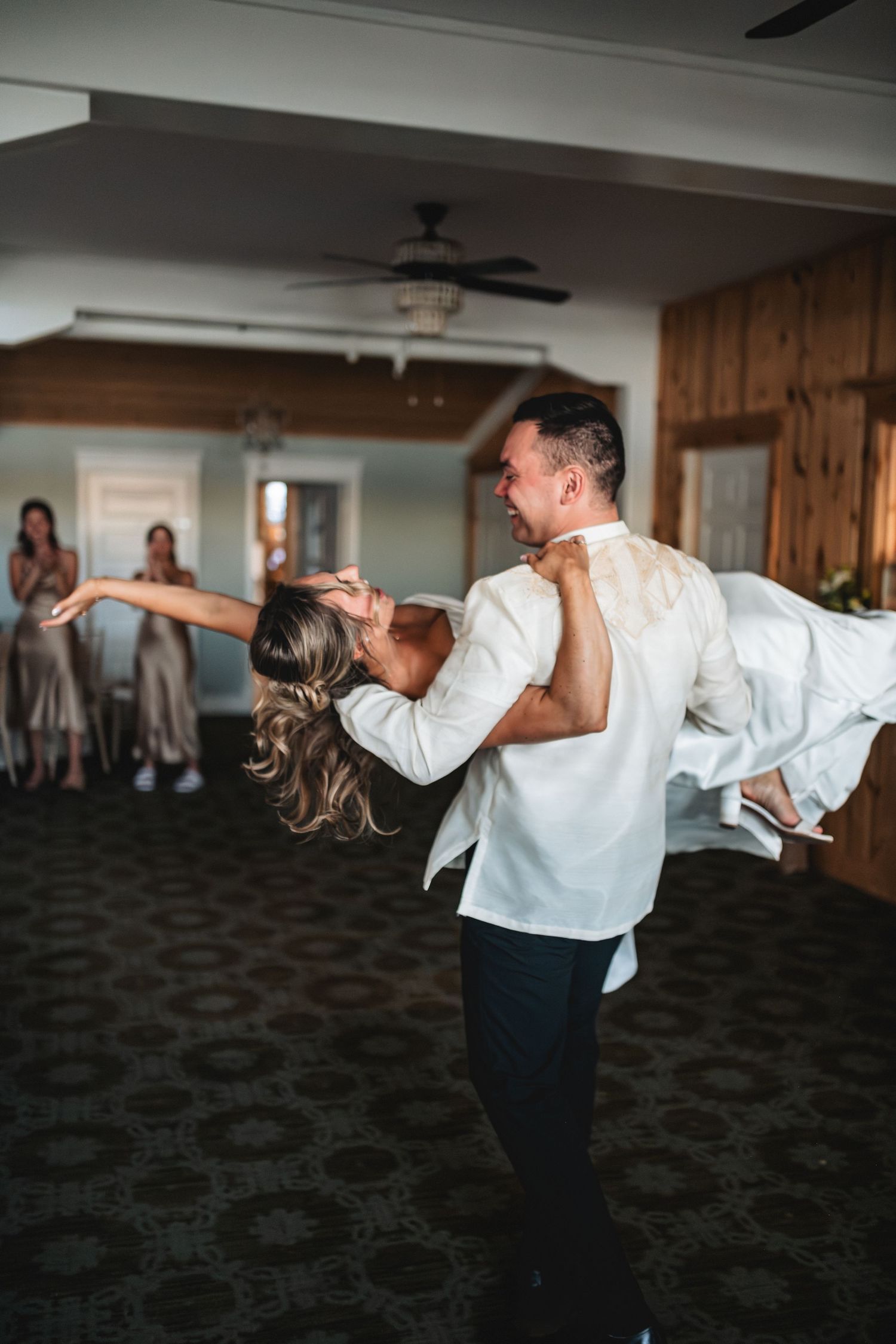 A couple performs a dramatic dip dance move in formal attire on a dark carpeted floor.