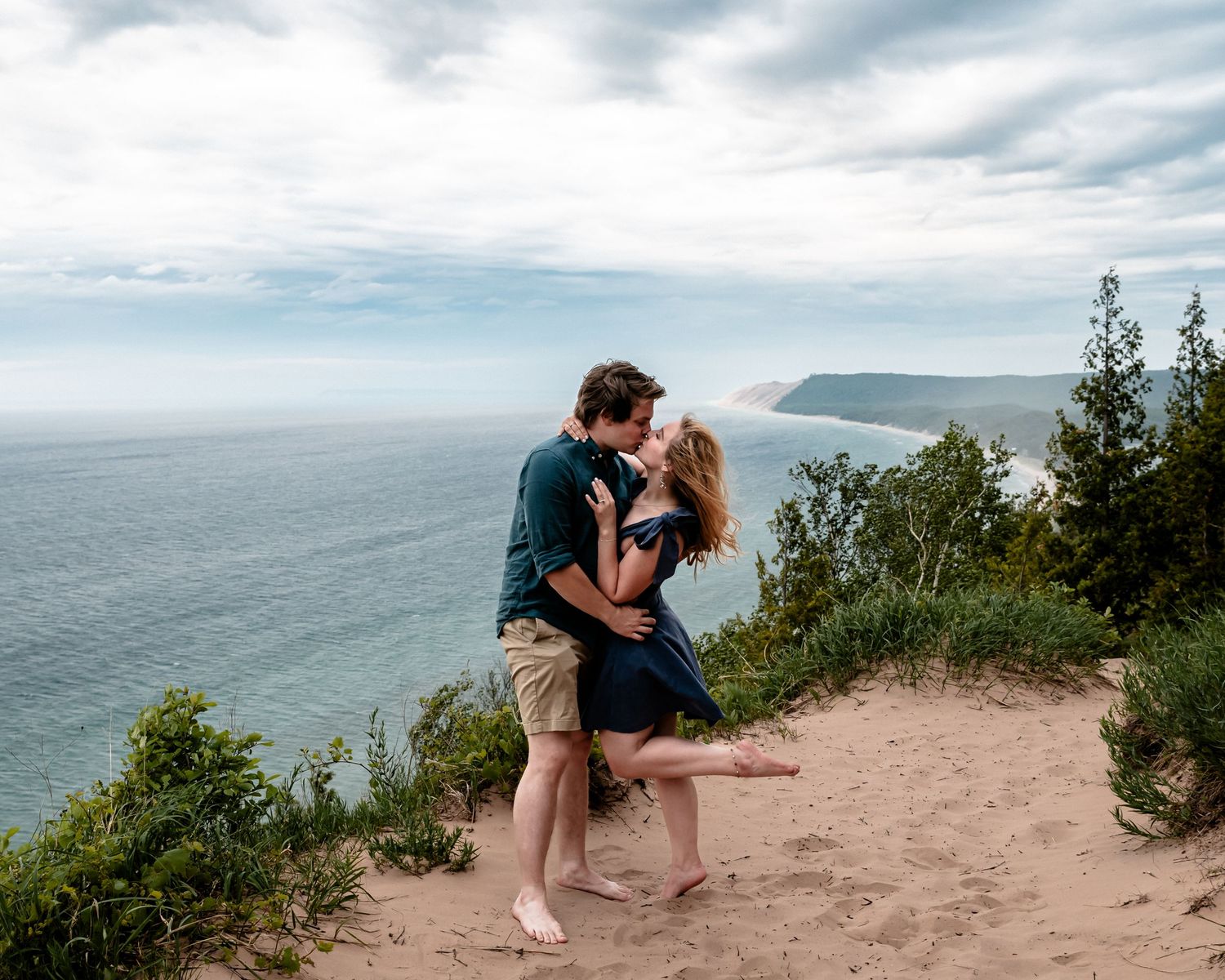 newly engaged couple share a kiss after a proposal on Empire Bluff Trail