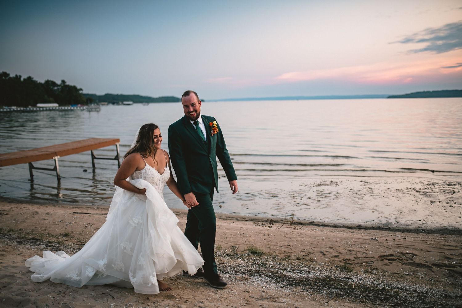 A romantic sunset beach wedding photoshoot with a couple walking along the shoreline at dusk.