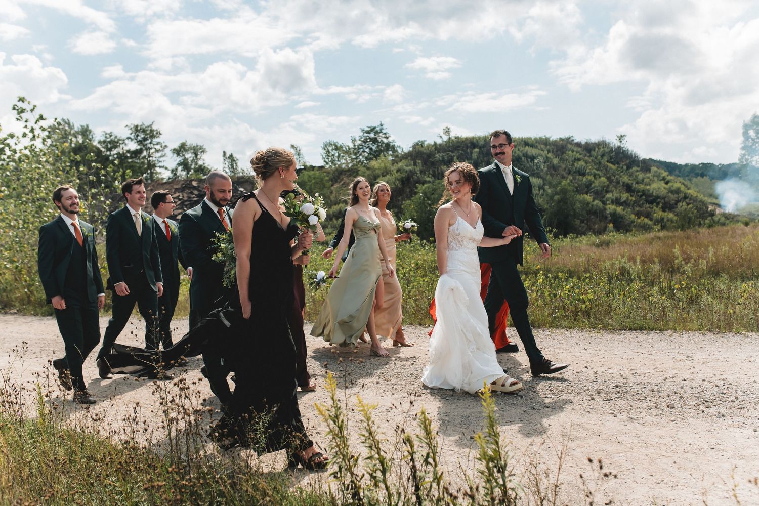 Wedding party members lined up on a scenic beach with mountains in the background.