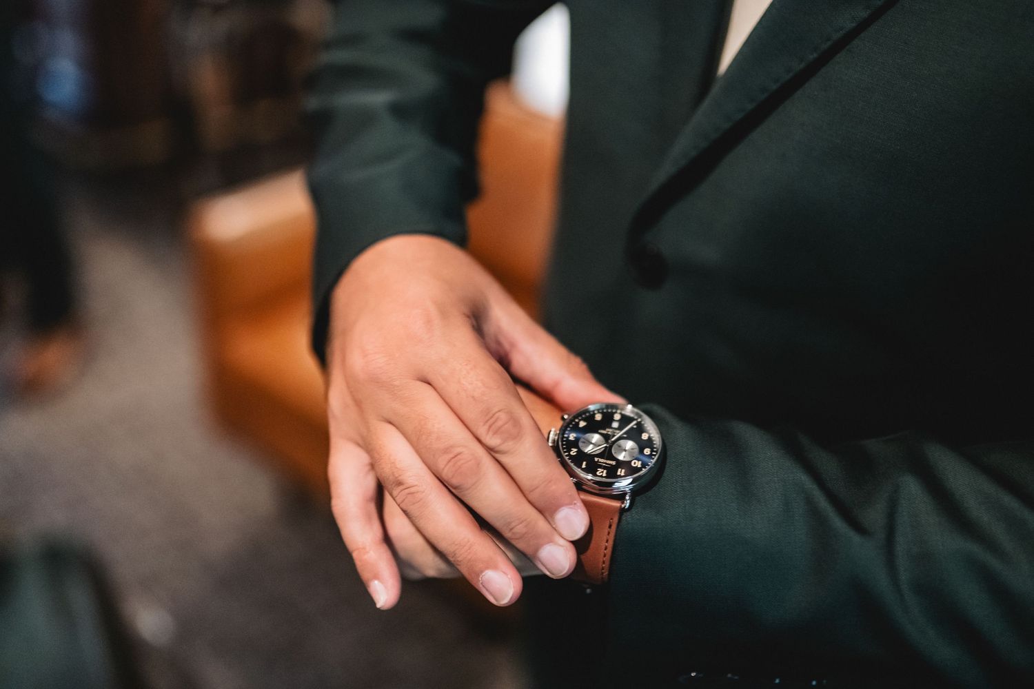 Man in dark green suit adjusting a family heirloom watch on his wedding day in Suttons Bay