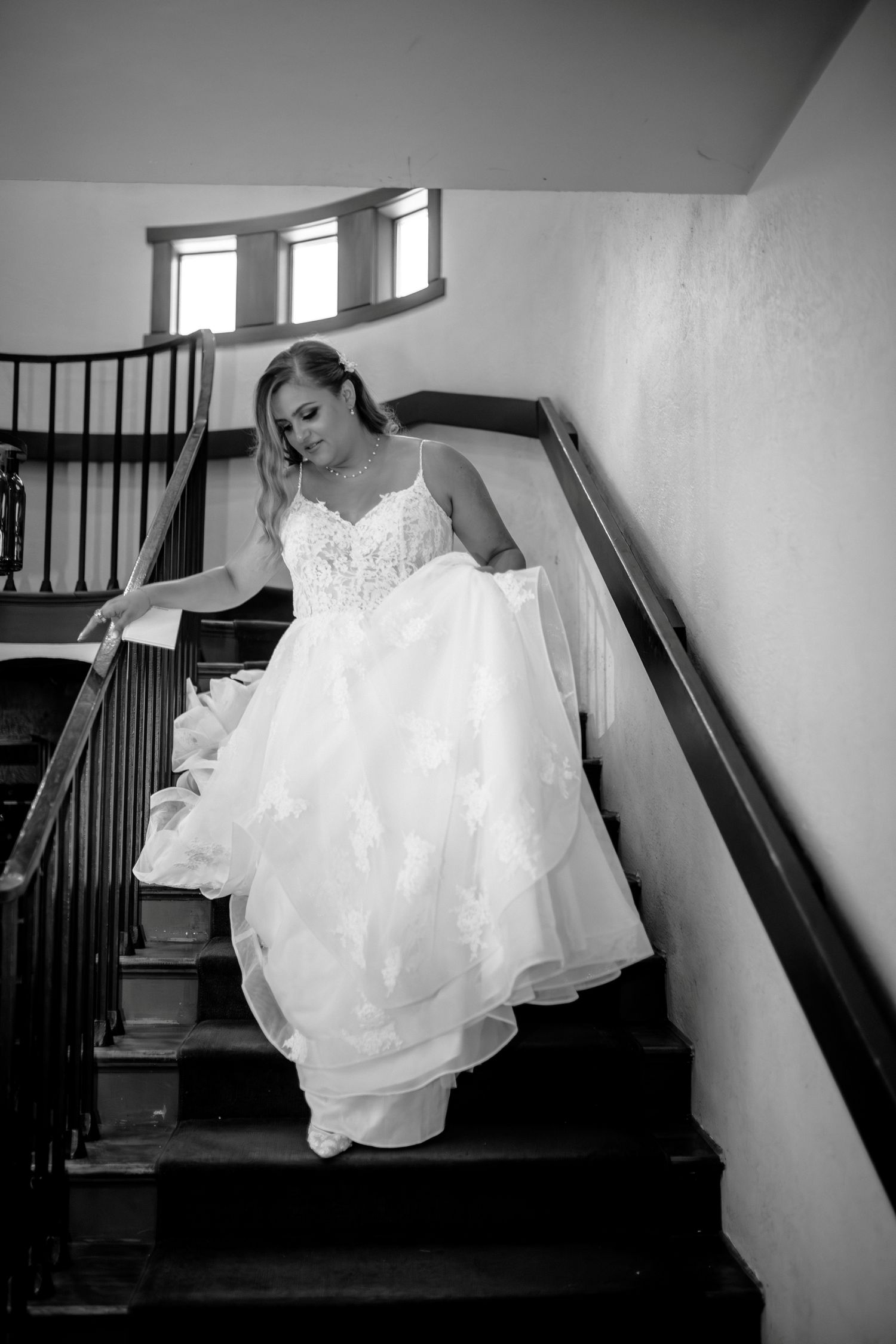 A sequence of black and white photos showing a person in a white wedding dress descending a staircase.