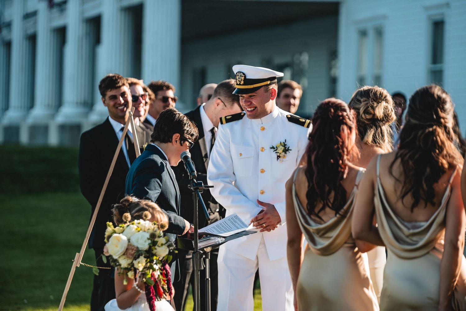 Wedding guests gather outdoors for a celebration with a mix of formal attire and casual summer clothing.