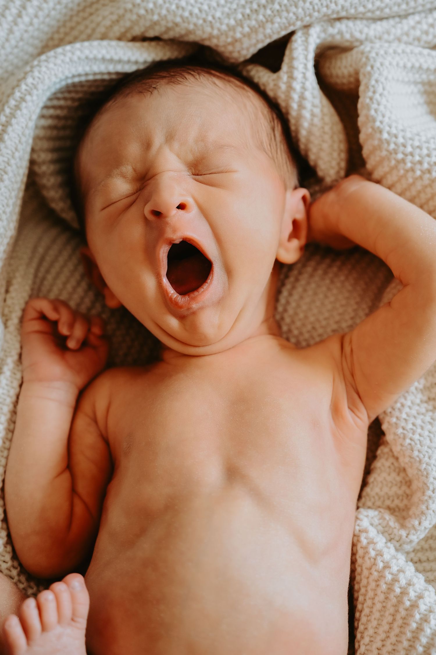 Baby cozy and yawing in his in home newborn lifestyle session in Thornton, Colorado