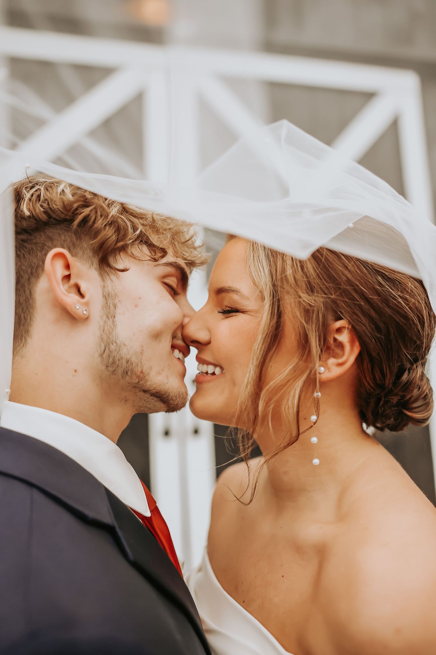 A romantic wedding photo capturing an intimate moment between newlyweds with a white veil.