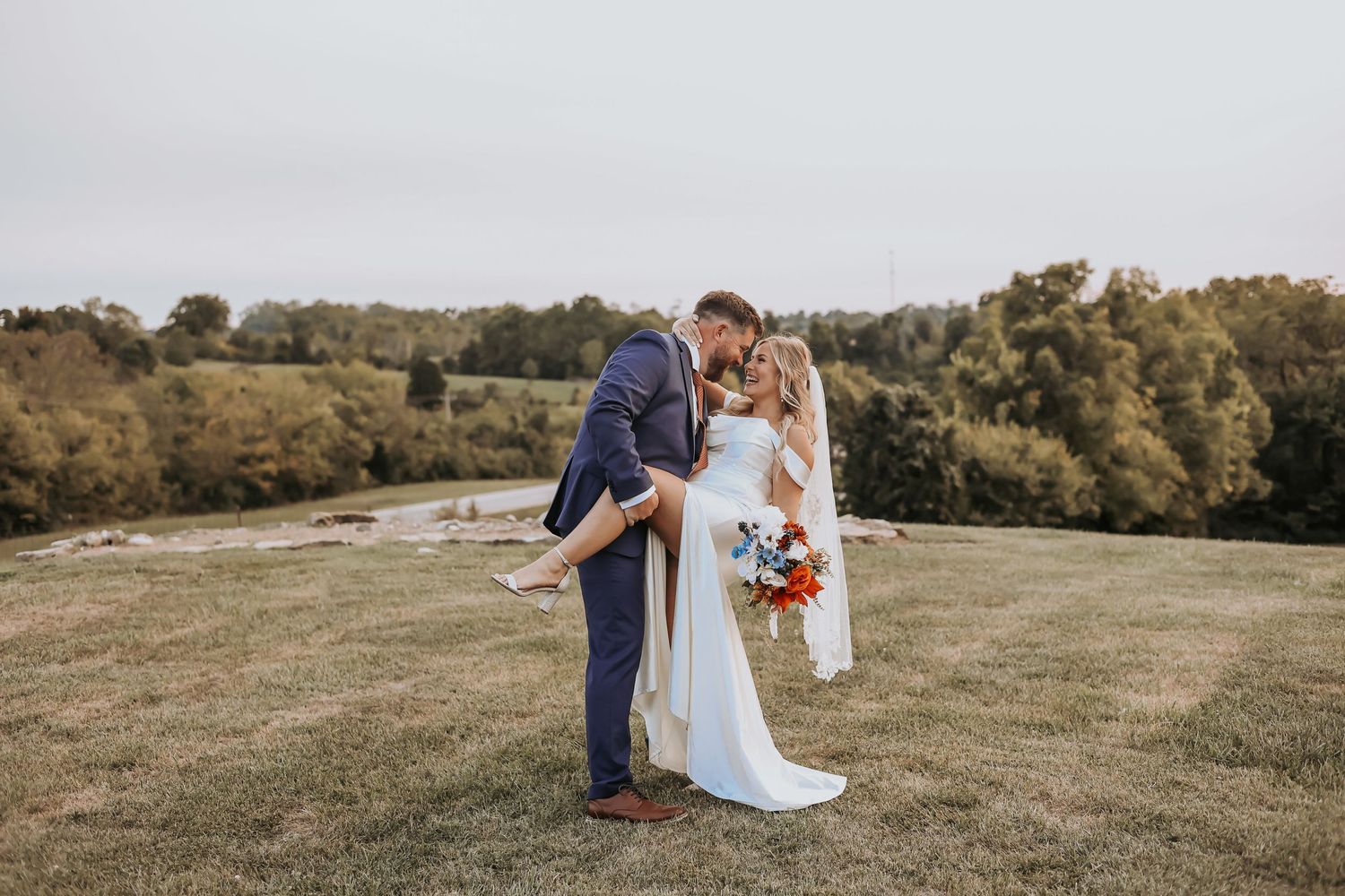 A romantic outdoor wedding scene on a hilltop with a blue and white color scheme and autumn landscape backdrop.