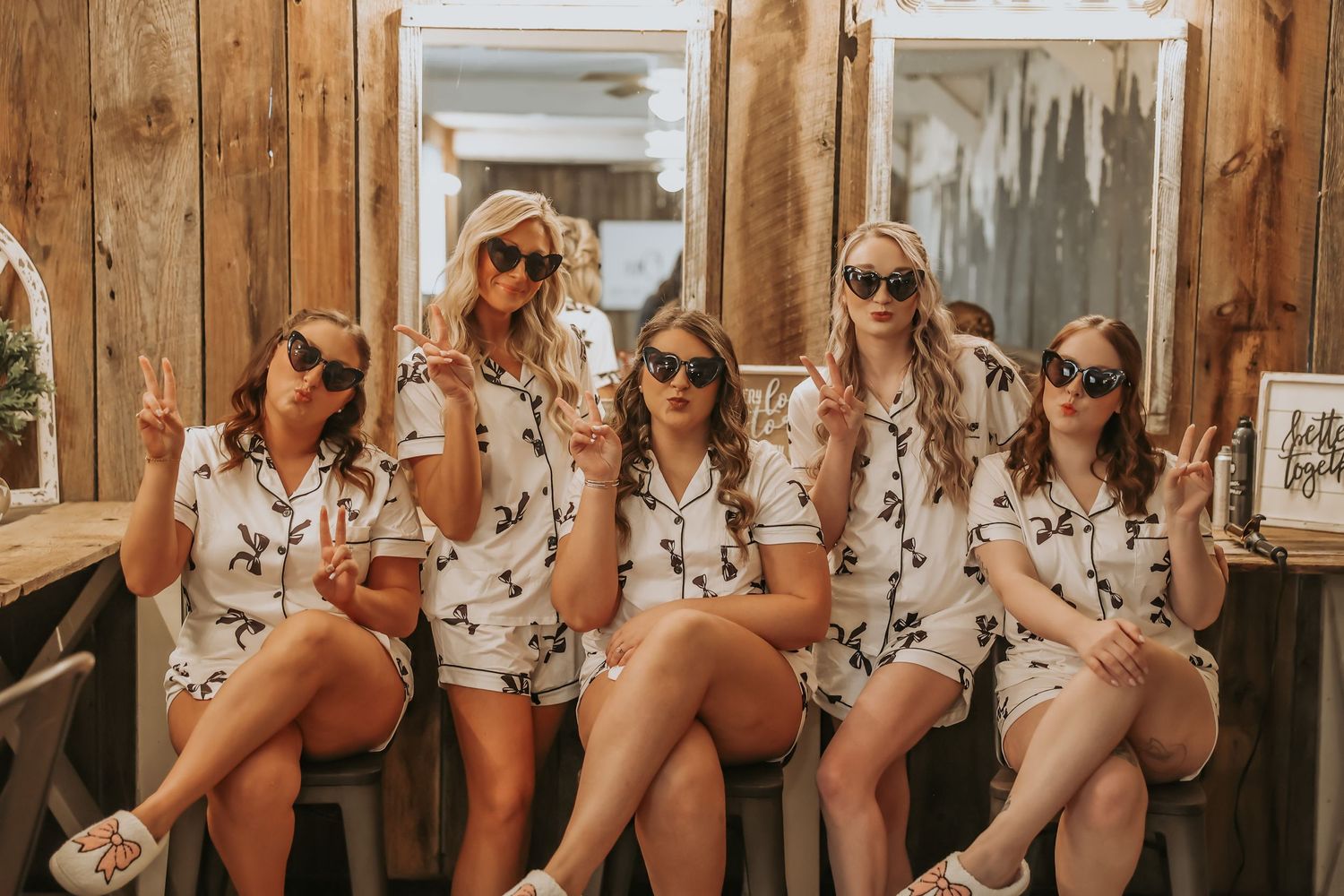 Group wearing sunglasses and matching floral outfits pose in rustic setting.