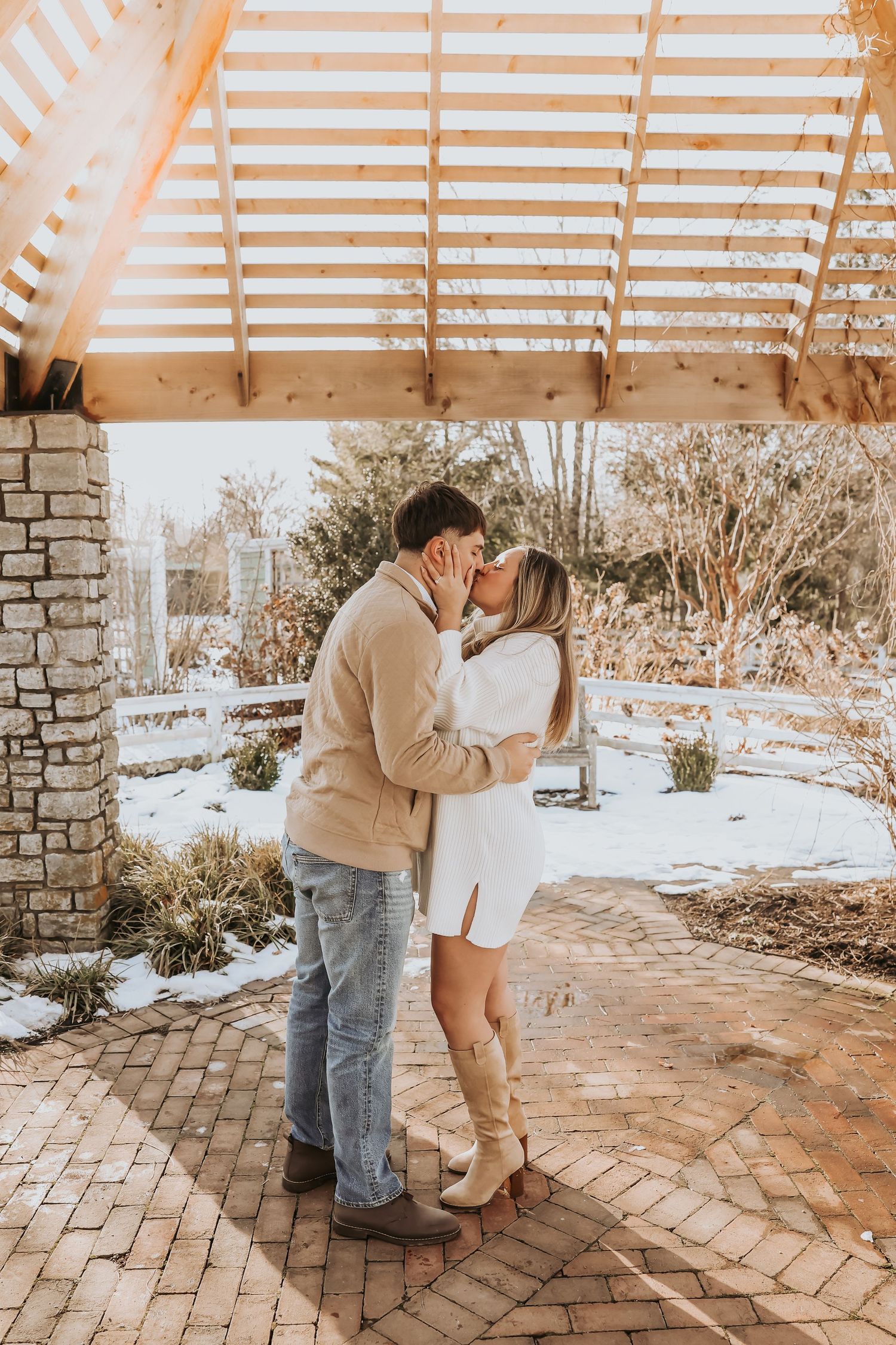 A couple shares a romantic moment under a covered porch during winter, with snow visible in the background.