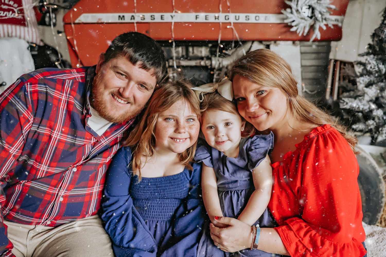 A group wearing coordinated red and blue outfits smiles together during a holiday photo session with Christmas trees.