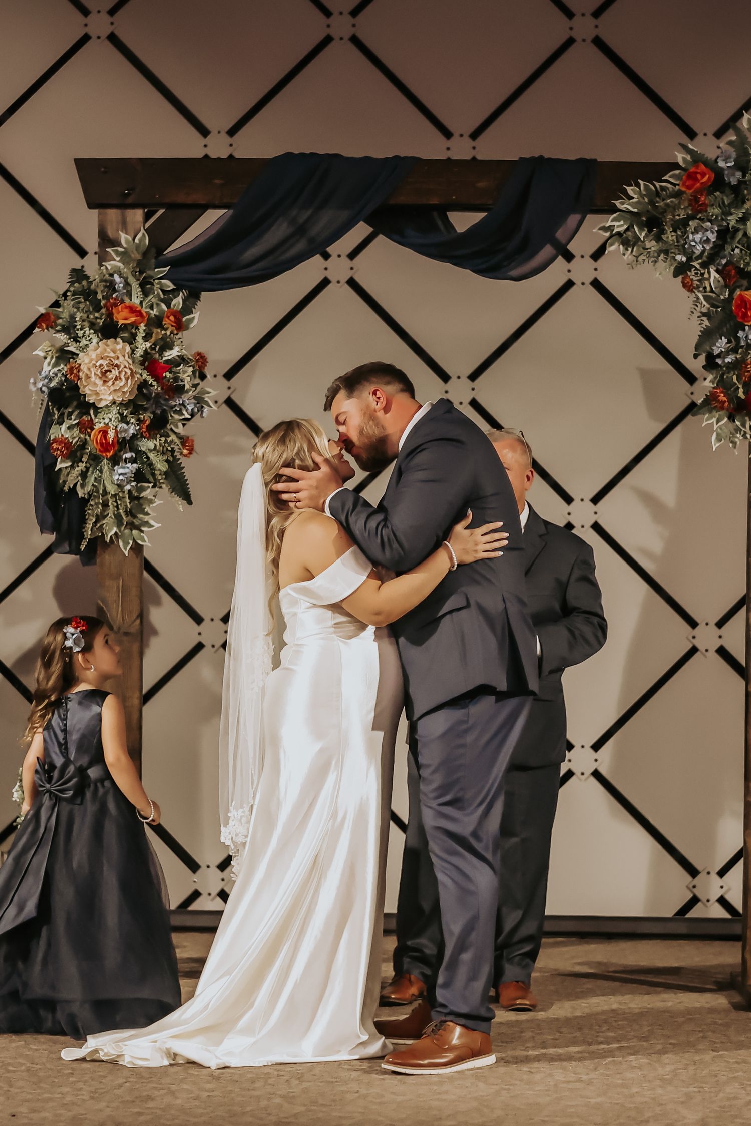 Wedding ceremony under an elegant arch with black draping and floral arrangements.