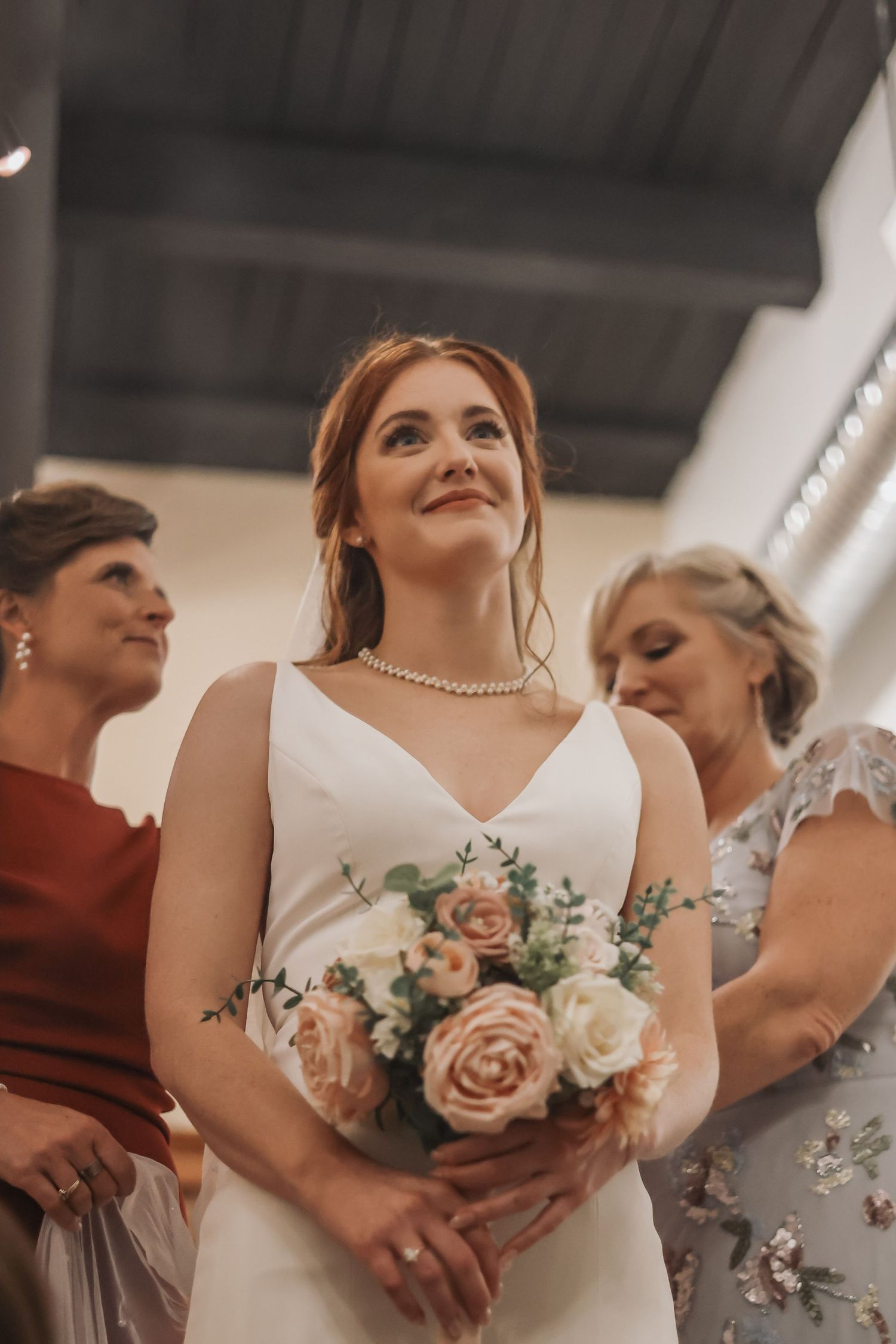 A wedding party moment showing elegant dresses and a beautiful bouquet of pink and white roses.