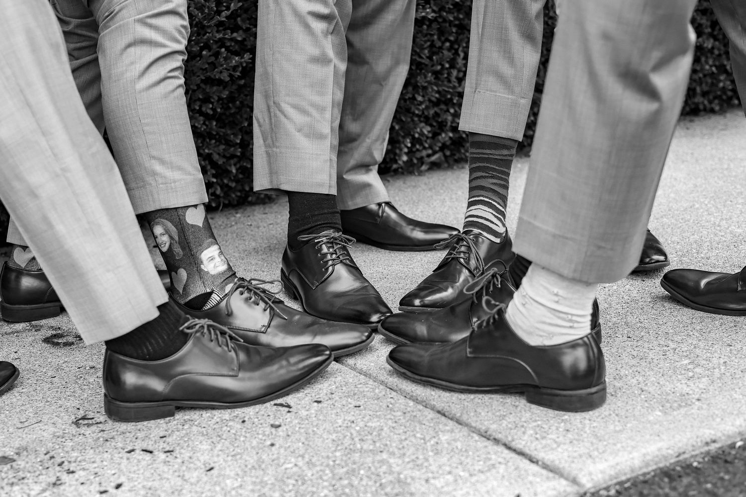 Black and white photo of formal shoes and socks worn by wedding party members.