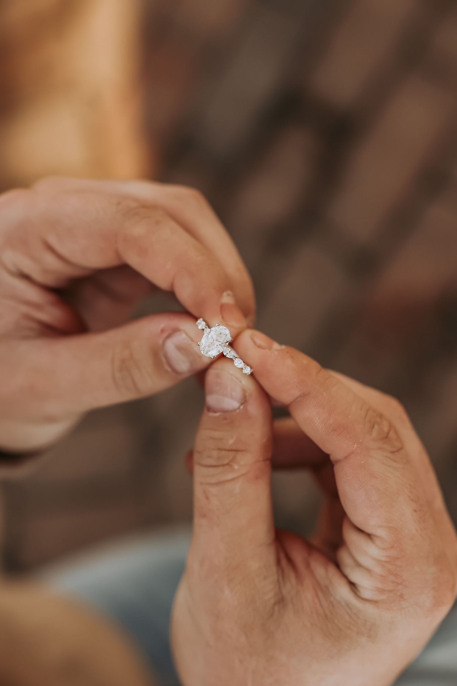 Close-up view of hands holding a delicate diamond engagement ring with a solitaire setting.