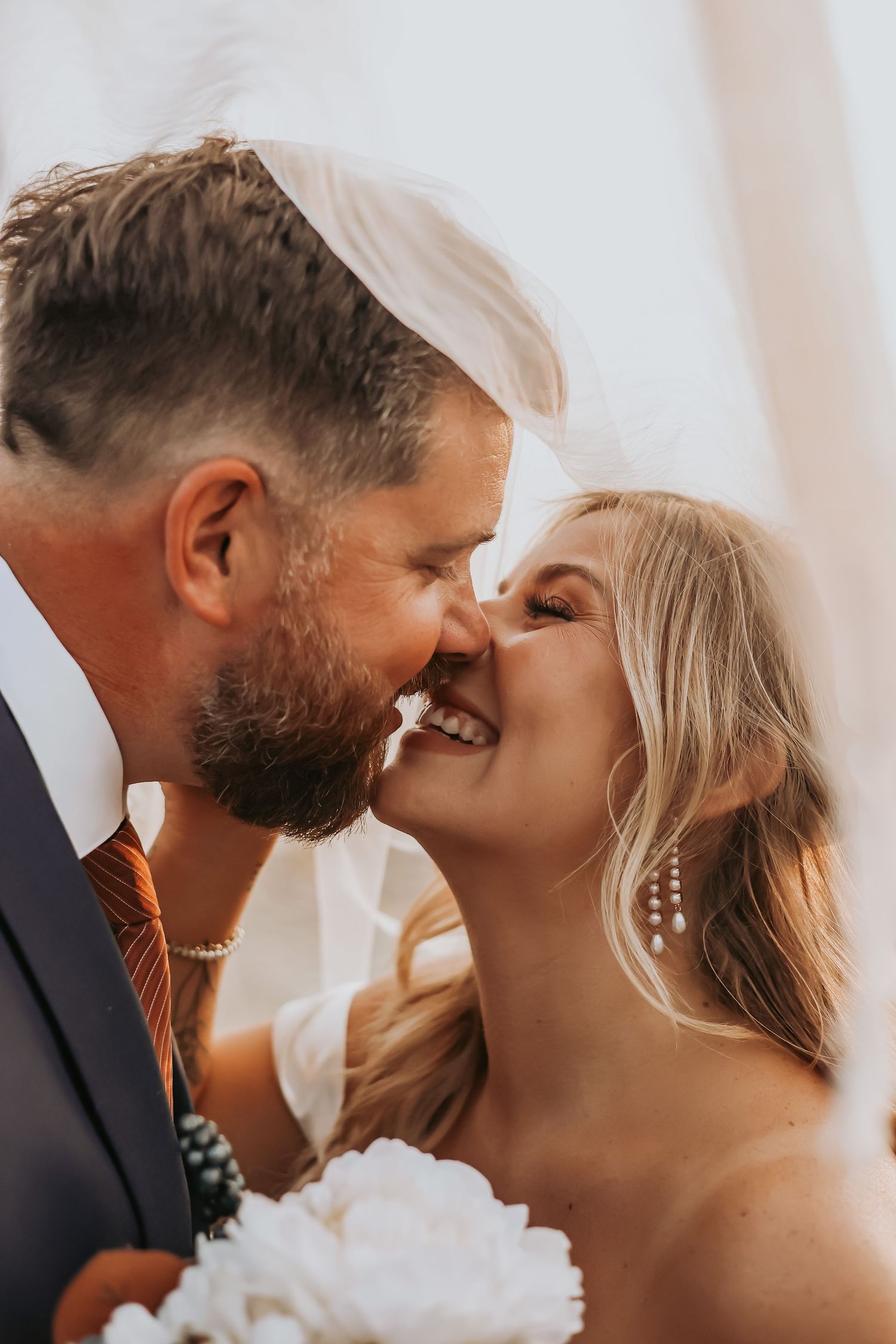 Close-up wedding photo captures romantic nose-to-nose moment between newlyweds.