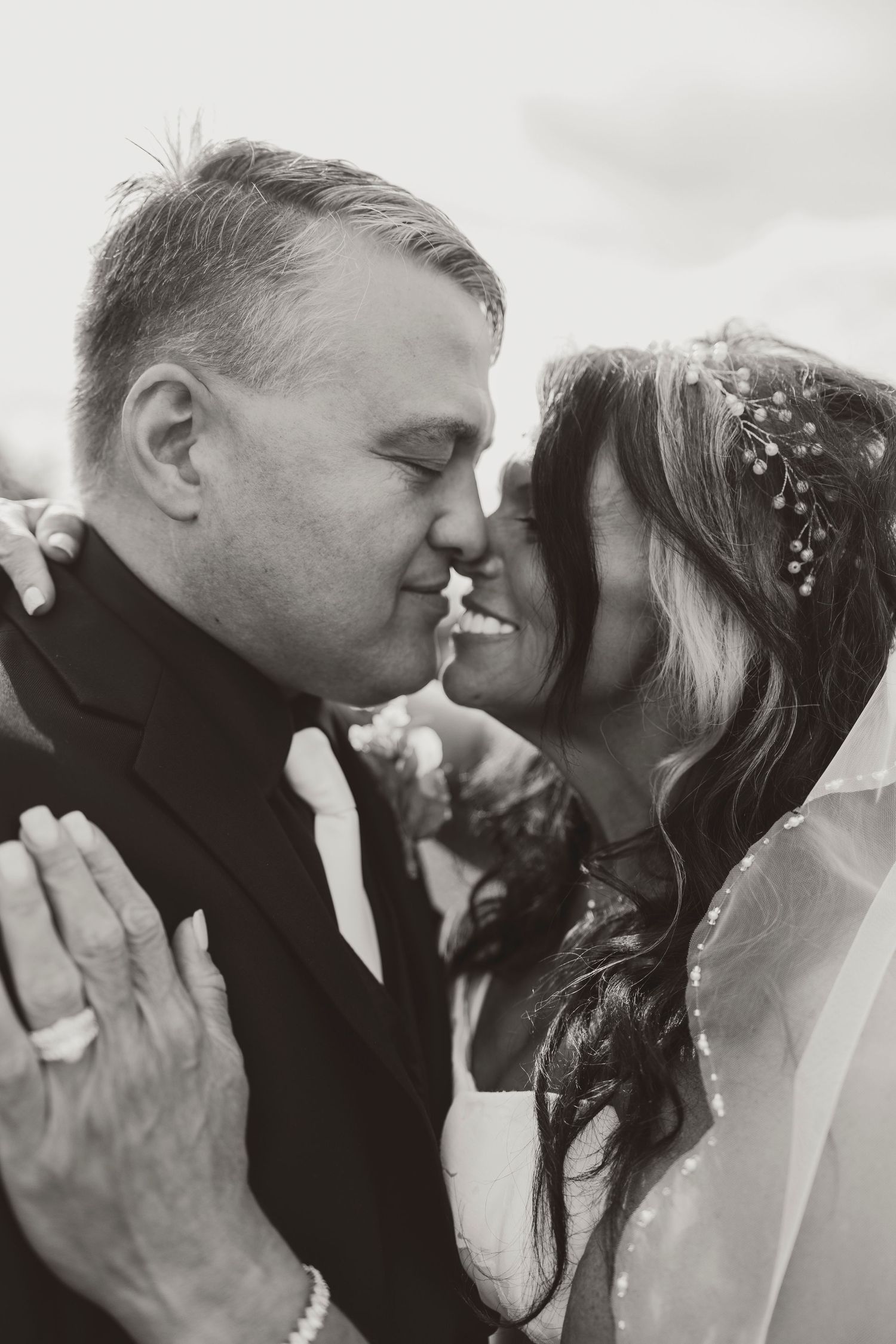 Black and white photo of bride and groom sharing a romantic moment, nearly kissing on their wedding day.