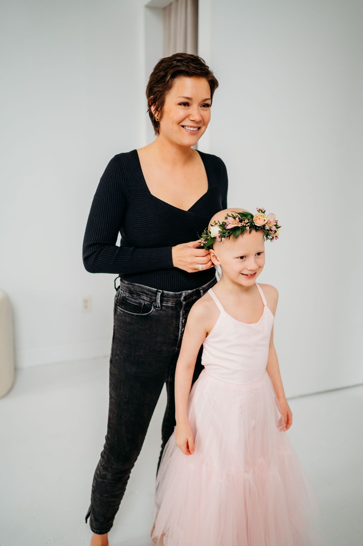 A sweet moment captured while placing a floral crown on a child wearing a pink tulle dress.
