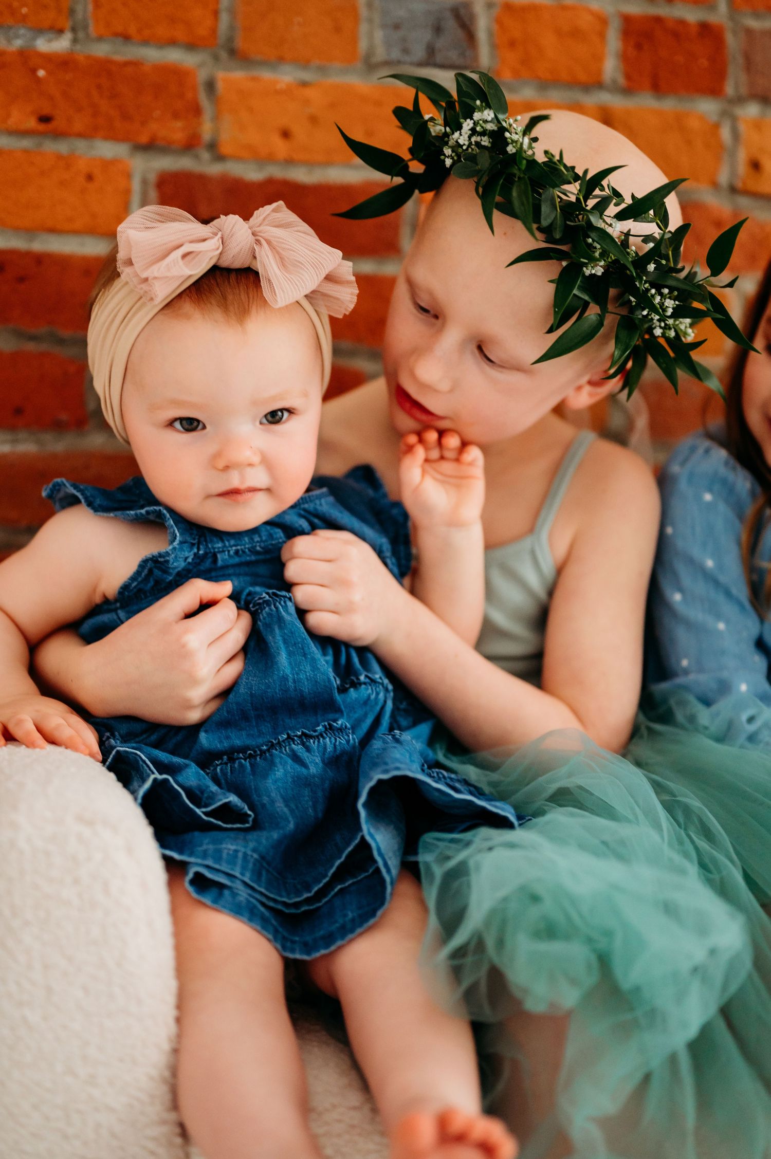 Baby wearing denim romper and mint tulle skirt poses against orange brick wall in sequence of candid shots.