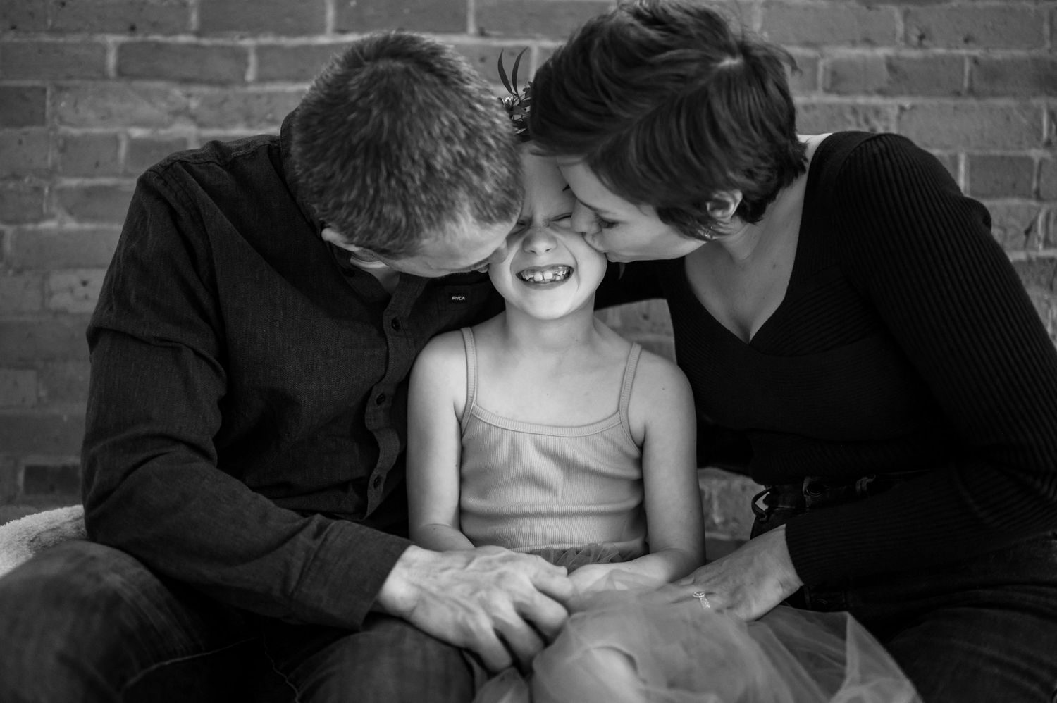 A joyful black and white portrait showing a candid family moment of shared laughter and affection.