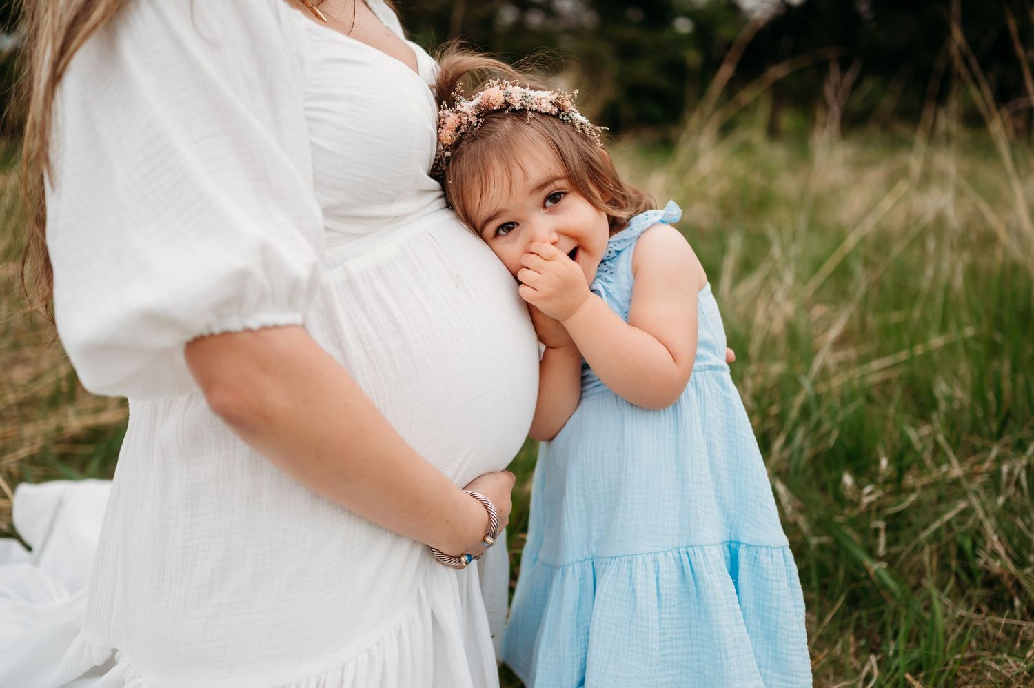 A collage of tender maternity photos showing a woman in white touching her belly alongside a child in blue dress.