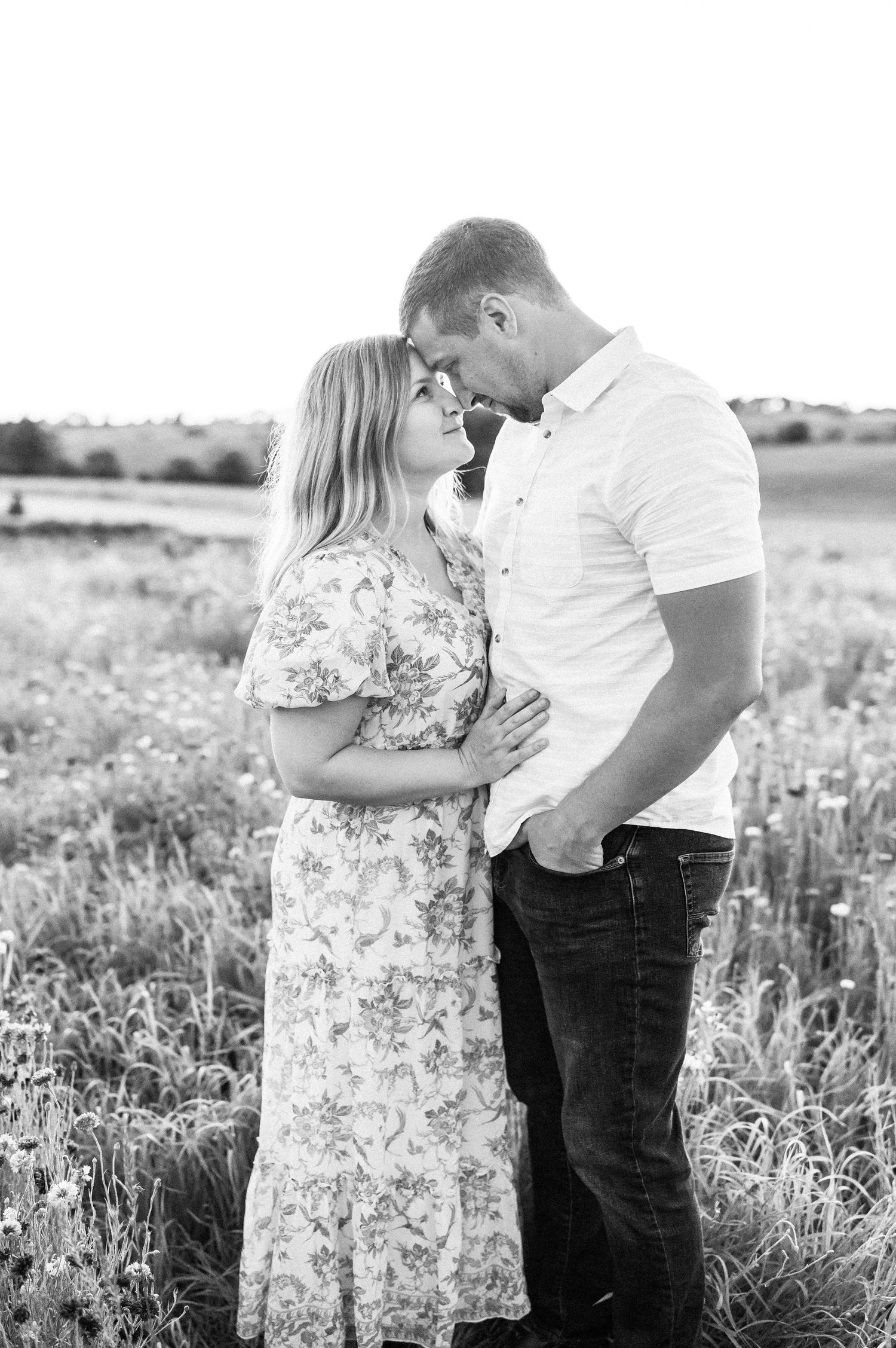 A romantic couple shares tender moments in a wildflower field with black and white photos showing their embrace at sunset.