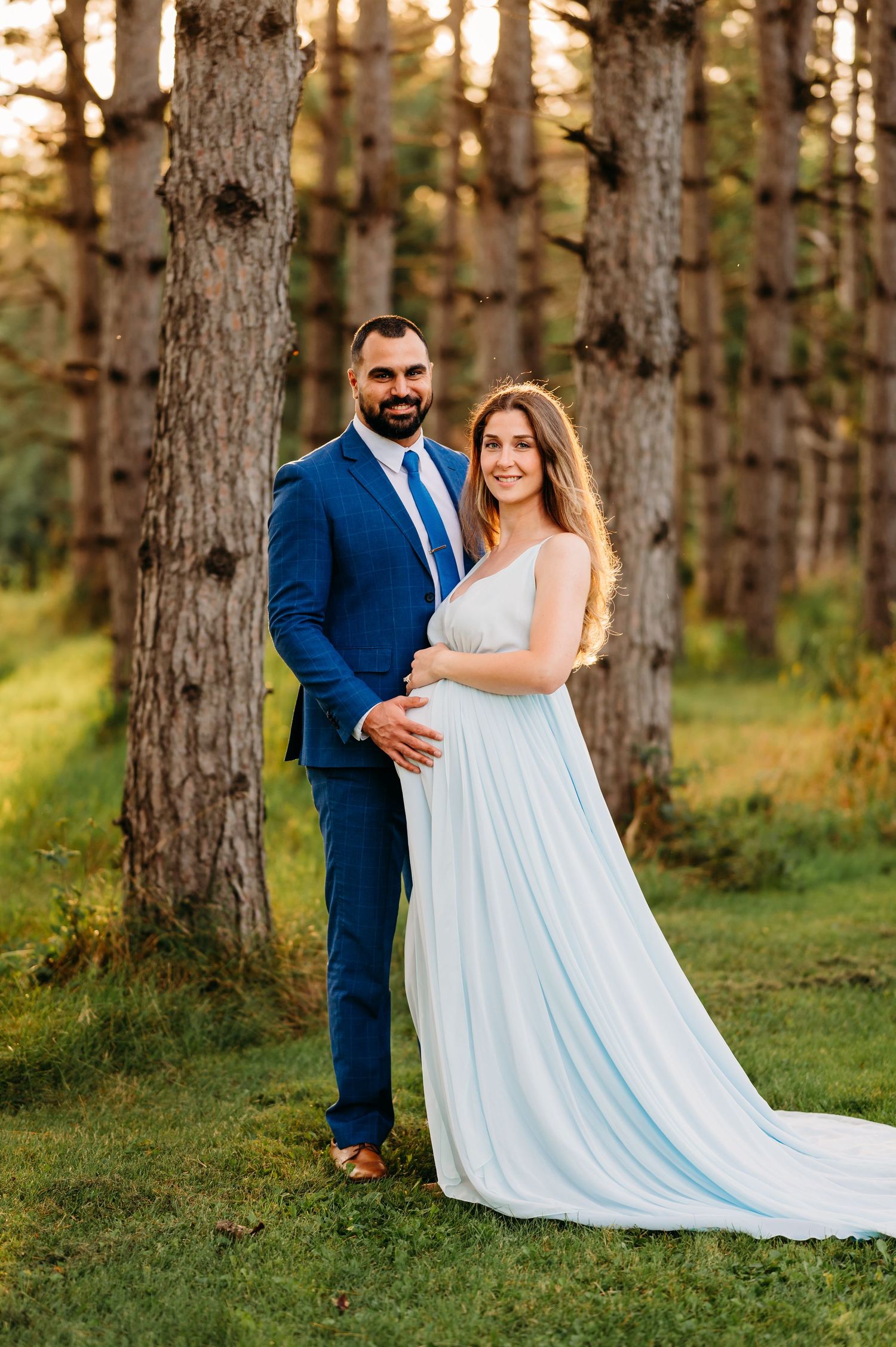 A couple in wedding attire pose for romantic photos in a serene pine forest setting.