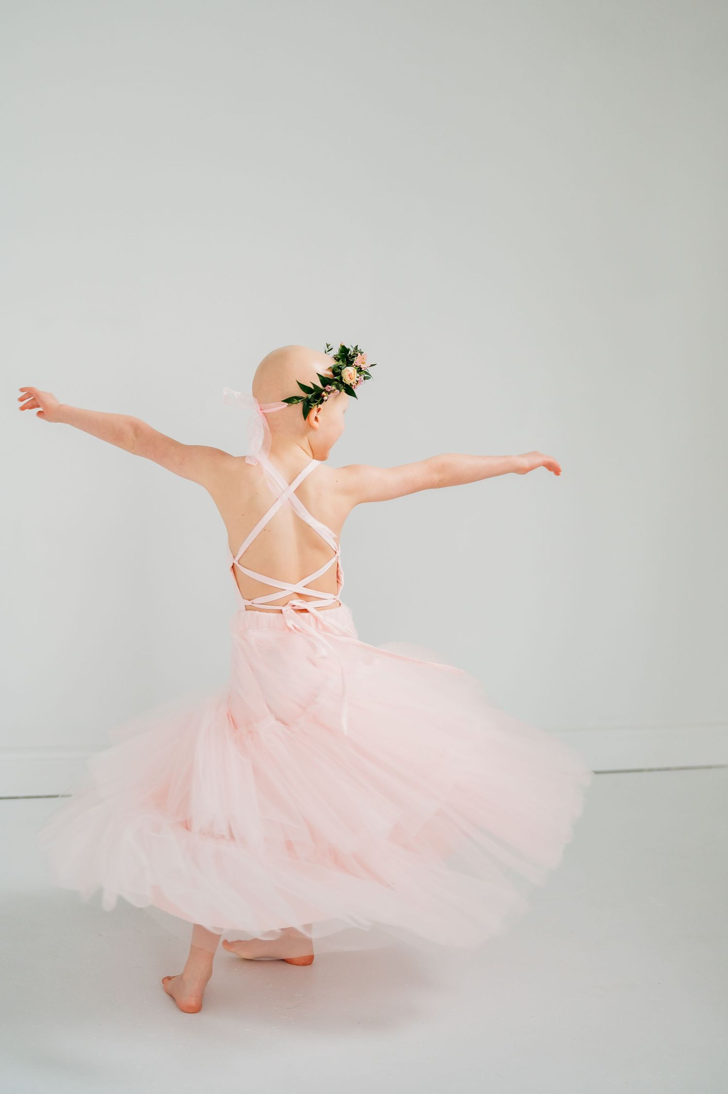 A sequence of photos showing a young dancer in a pink tutu dress twirling and posing against a light gray backdrop.