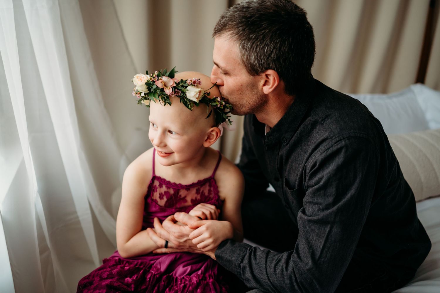 A heartwarming moment captured in burgundy and black tones showing tender family interaction on a couch.