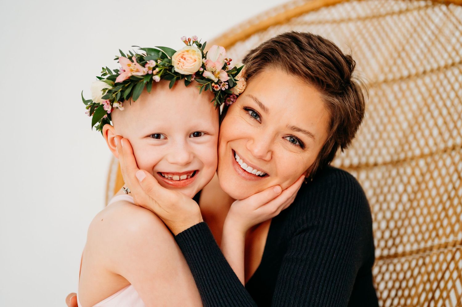 Joyful candid moments captured against a woven rattan chair backdrop with soft lighting and warm expressions.