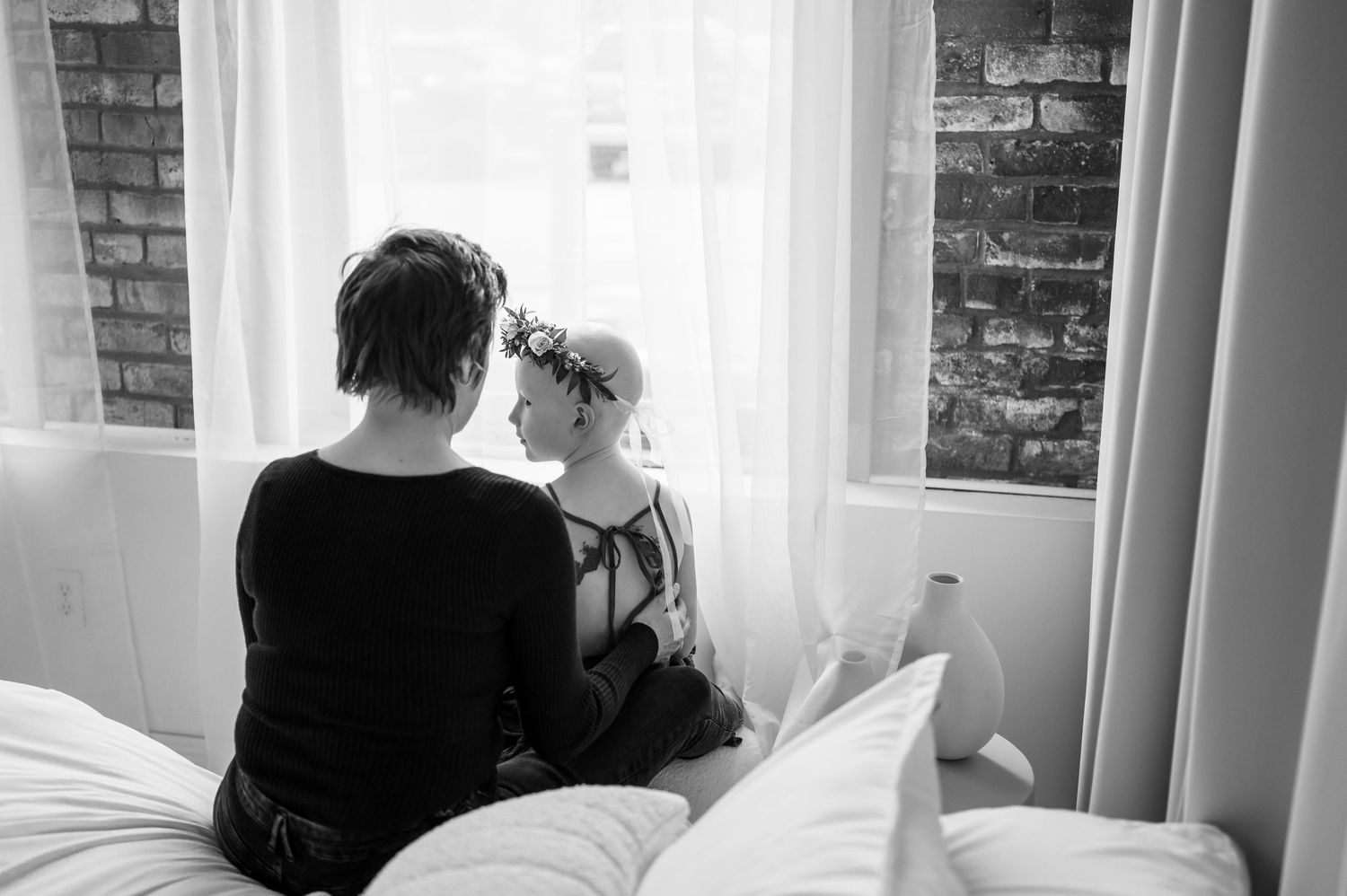 Black and white intimate portrait session with soft window light and exposed brick walls.