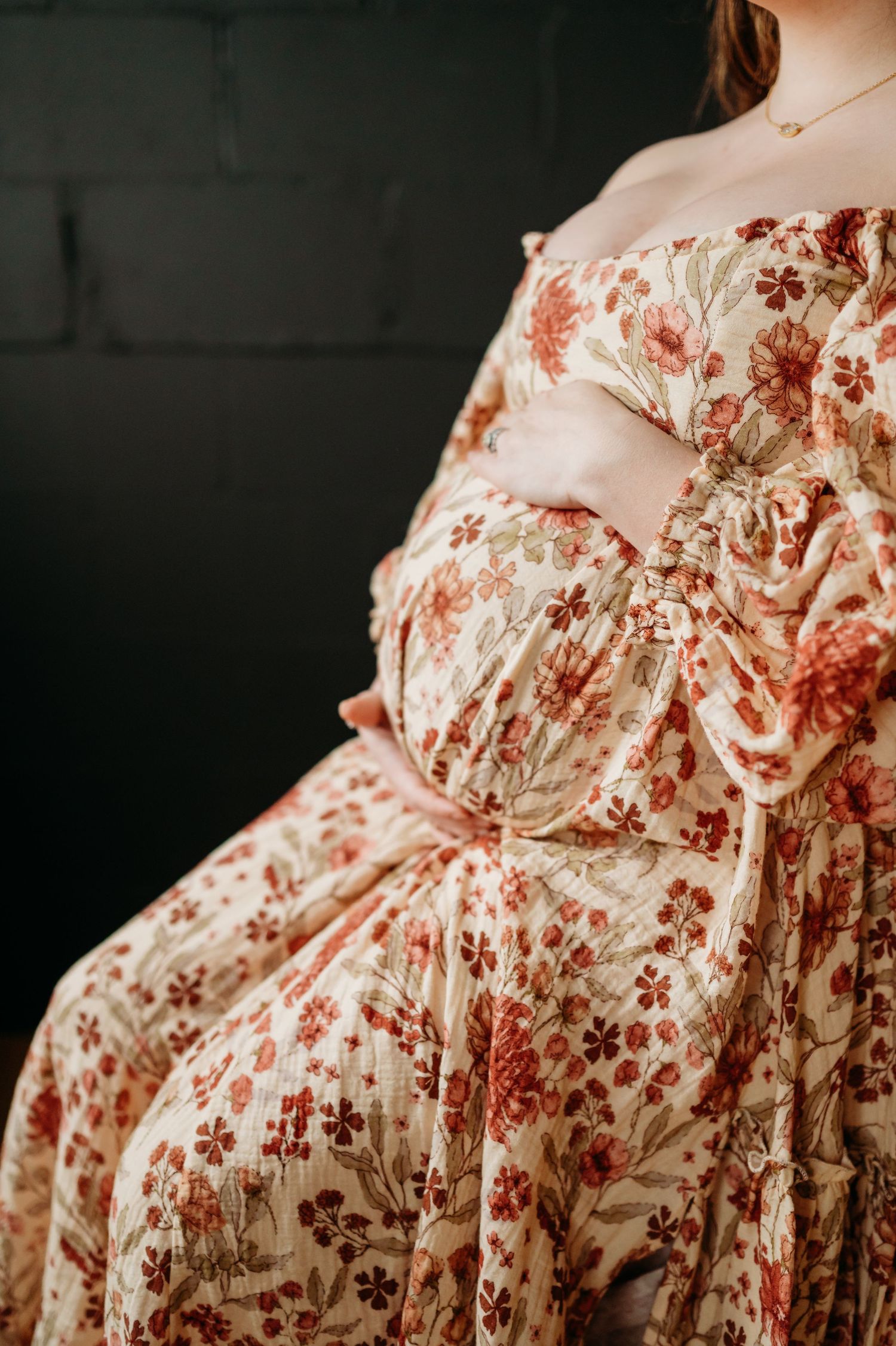 Close-up view of a floral maternity dress with romantic red and cream floral patterns on flowing fabric.