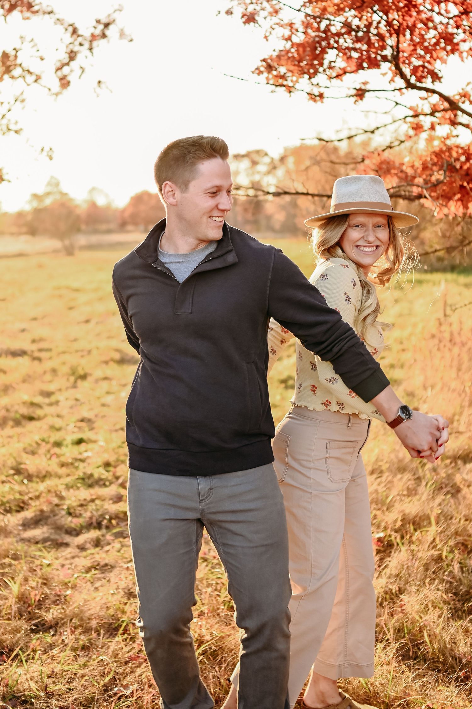 A couple shares a romantic moment in a golden autumn field during sunset, creating a warm and intimate atmosphere.