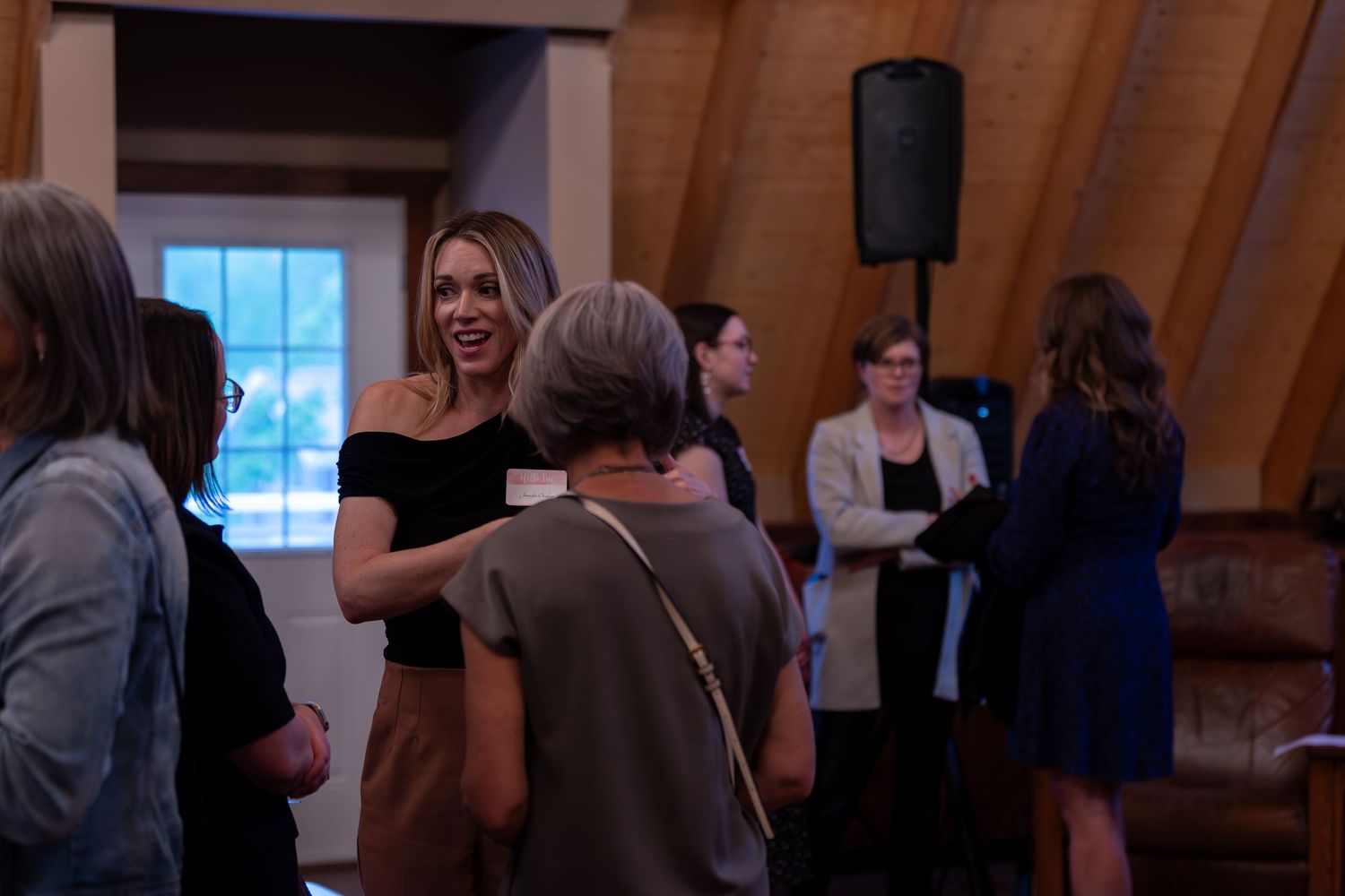 Women socializing and networking inside a rustic barn event venue.