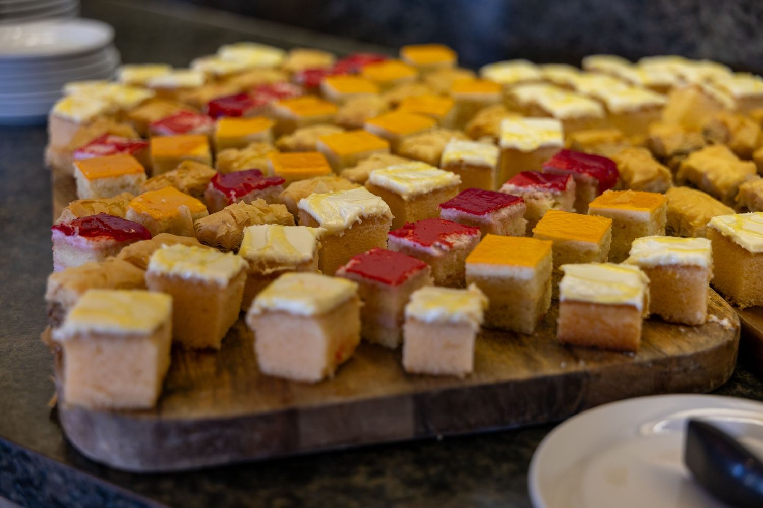 Assorted cheese and bread canape bites arranged on a wooden serving board for a party or catering event.