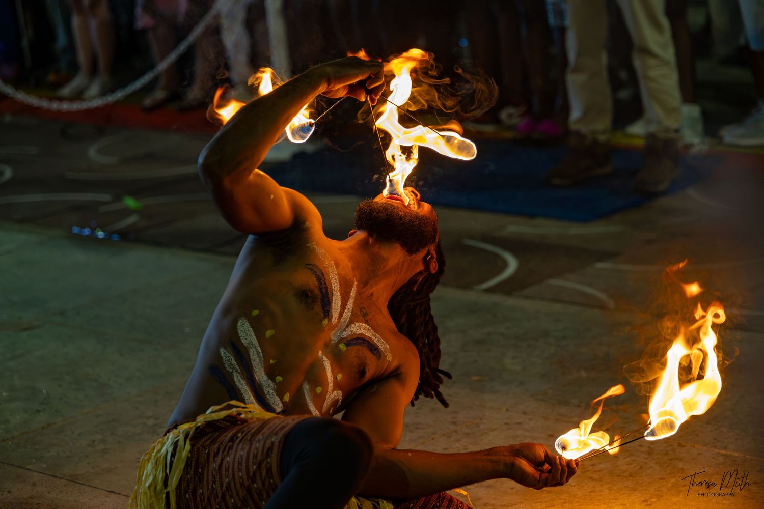 A fire performer bends backward during a dramatic fire-eating act at a nighttime cultural show.