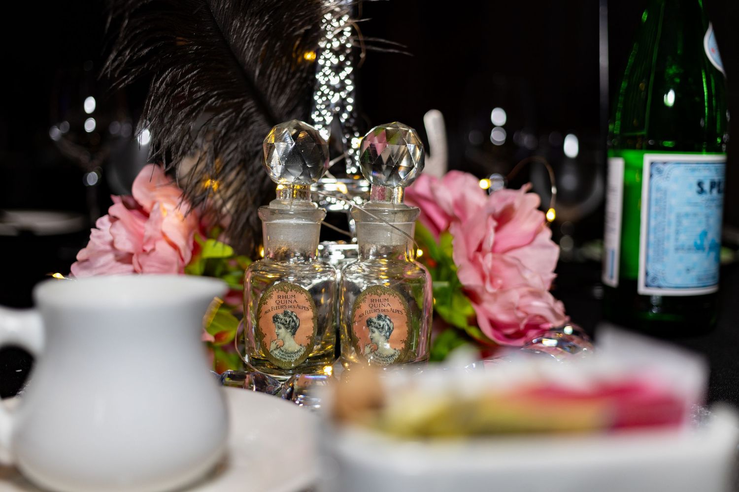 Decorative crystal salt and pepper shakers with pink peonies and wine bottles on an elegant restaurant table setting.