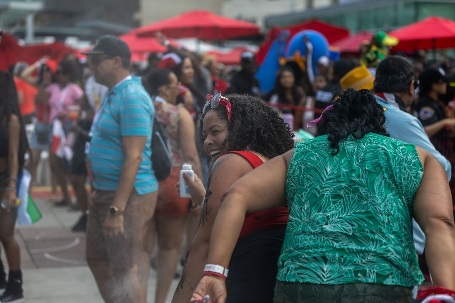 People cooling off in water mist spray at crowded outdoor summer festival event.