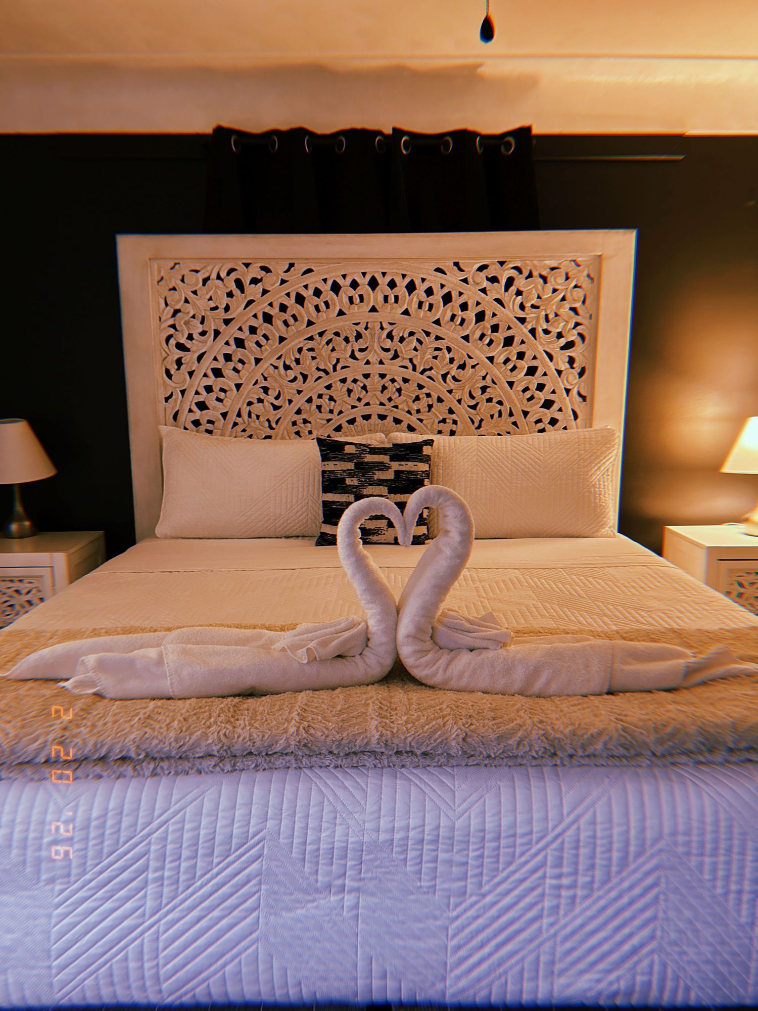 A series of hotel bed photos showing towel art swans and decorative headboards in a romantic evening setting.