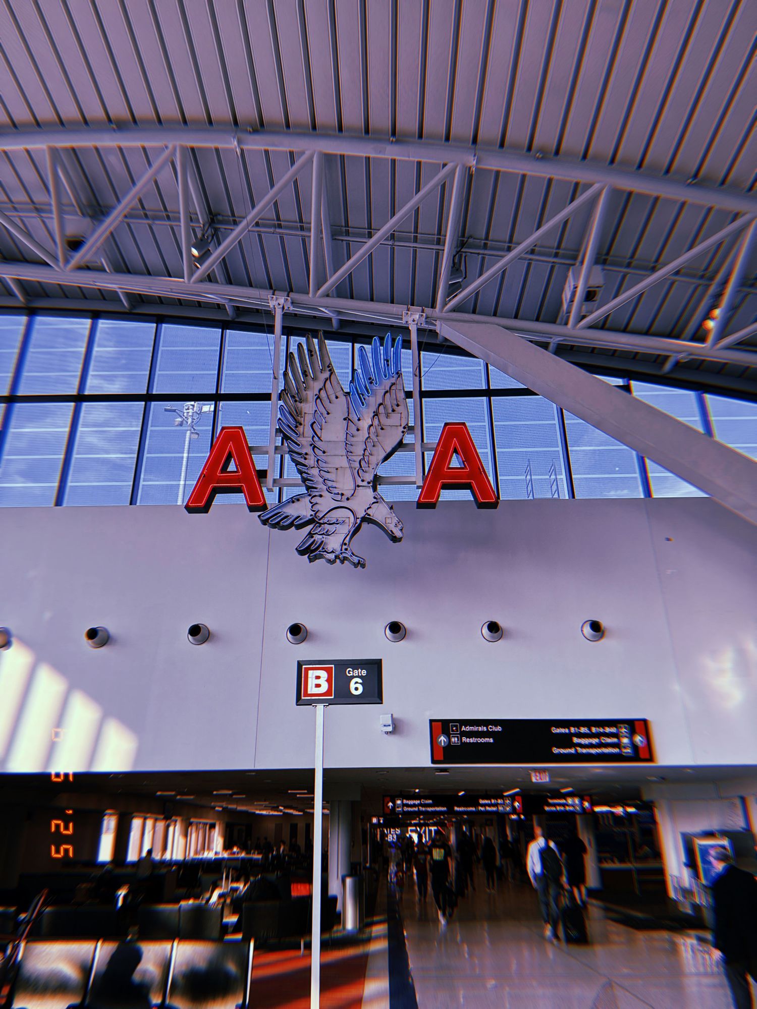 Airport terminal interior showing ADA logo and eagle emblem with gate B5 visible underneath.