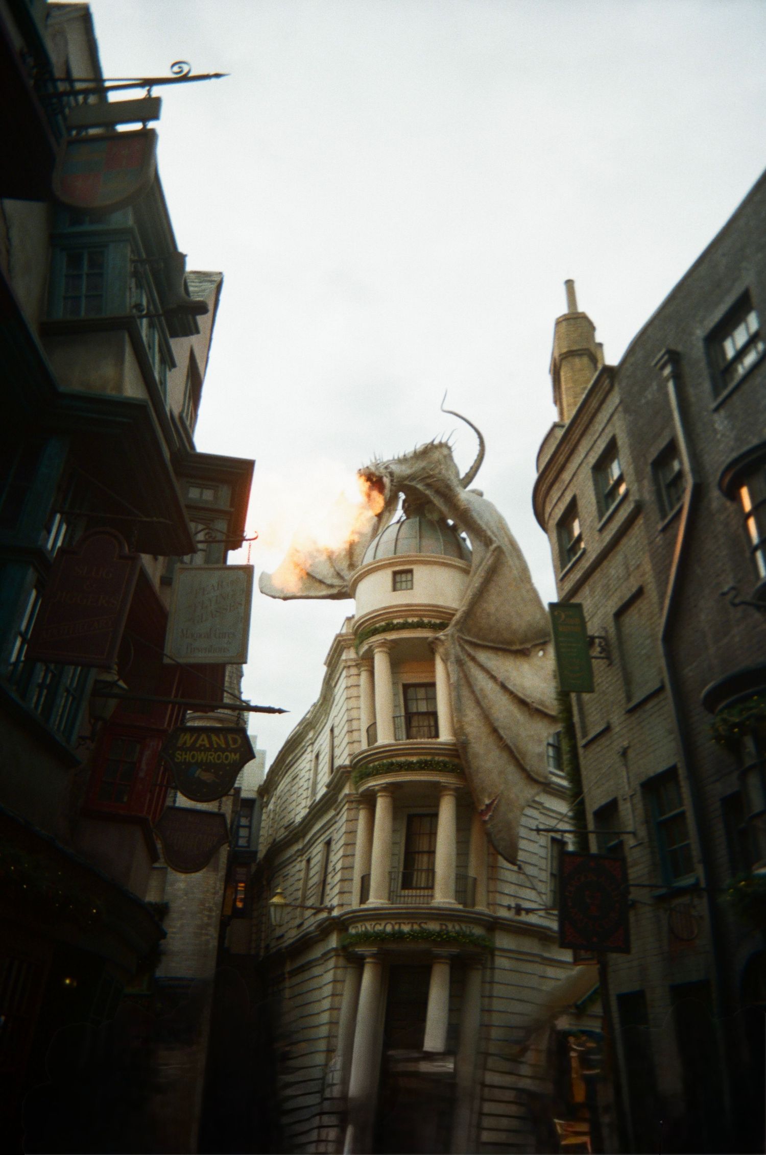 A dragon-shaped architectural feature perches atop a white stone building in Universal Studios' Wizarding World.