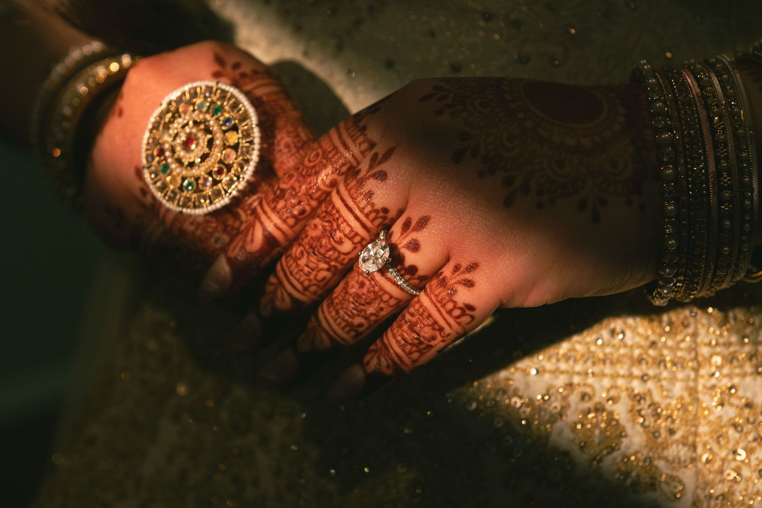 Intricate henna design and gold ring adorning hands in traditional Indian wedding style.