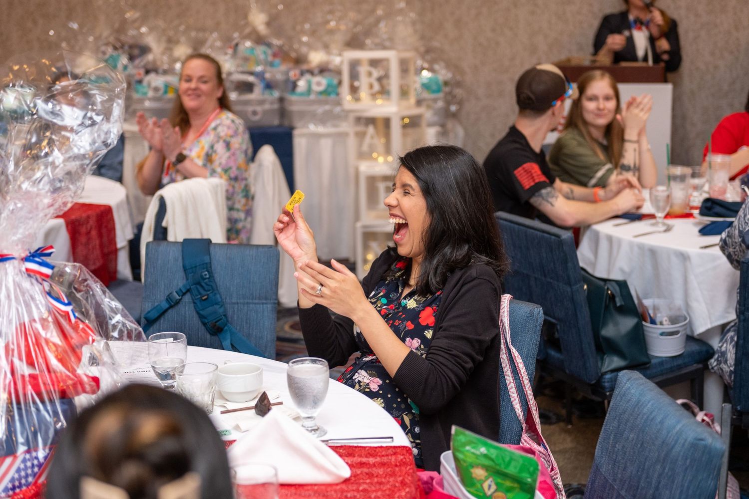 People gathered at tables participating in a festive holiday party with decorations and refreshments.