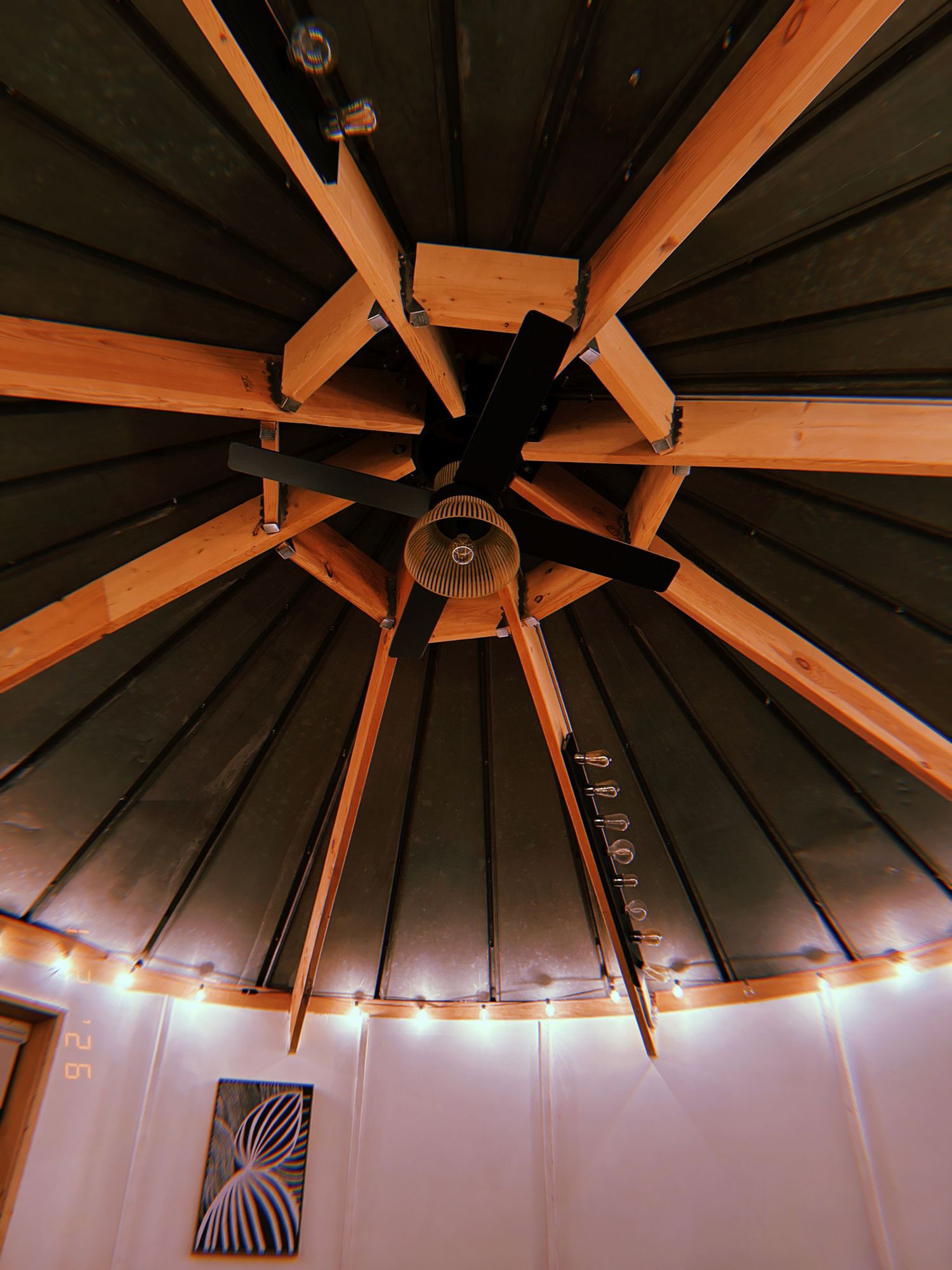 Architectural detail of a wooden octagonal ceiling with exposed beams radiating from center and recessed lighting around perimeter.