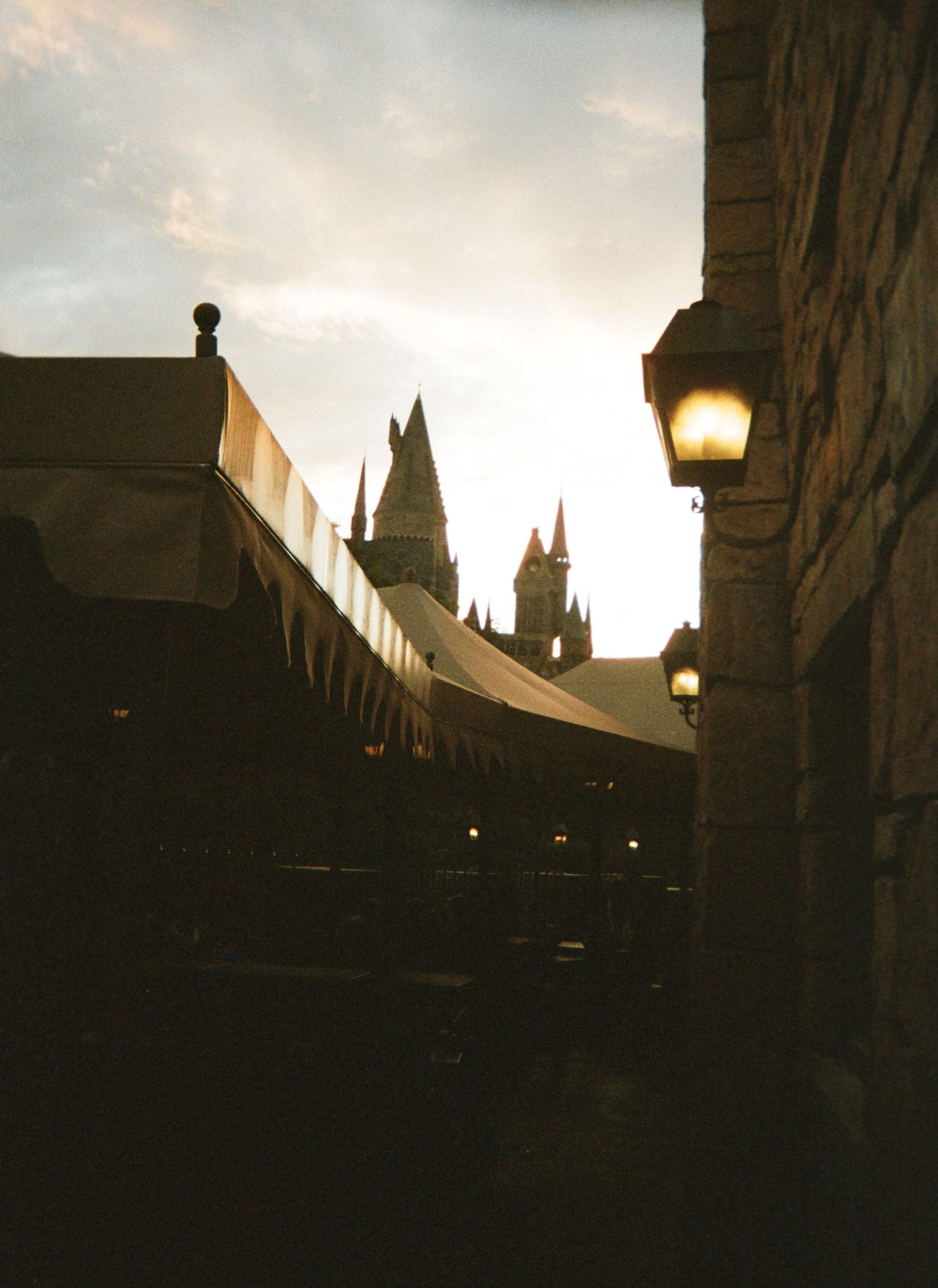 A dark silhouette of a Gothic church spire against a moody evening sky with glowing street lamps below.