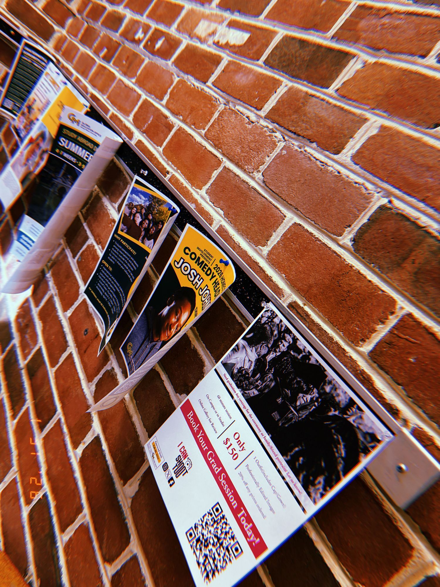 Brochures and flyers displayed against a red brick wall at an angle.