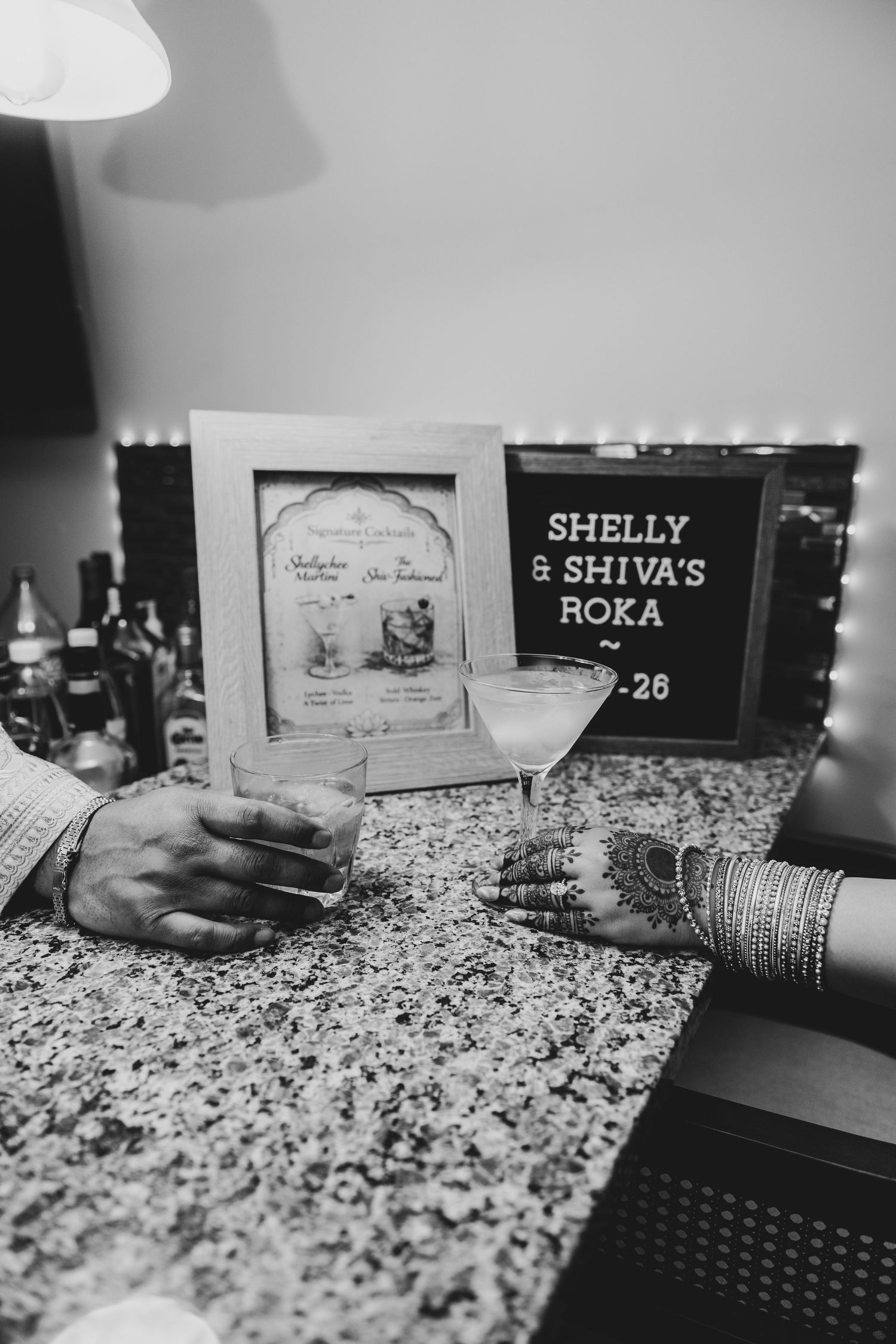 Black and white photo of a laptop keyboard with name tags and decorative items on a speckled granite countertop.