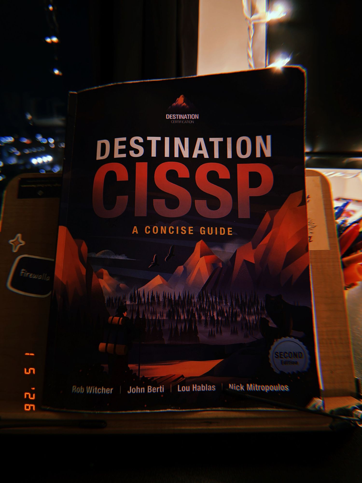 A row of technical certification and cybersecurity books on a dark shelf with titles including CISSP and Destination.
